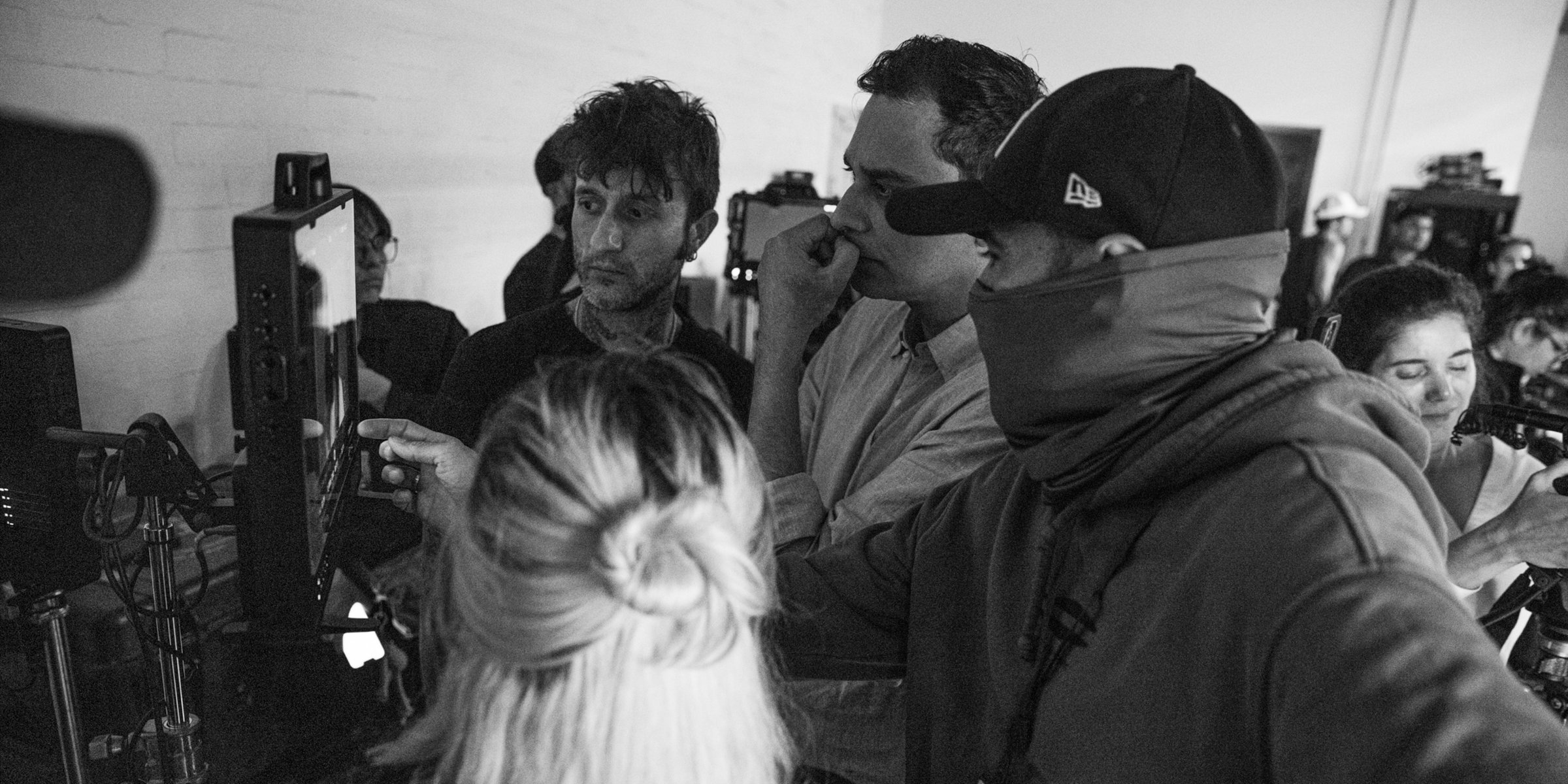 Black-and-white behind-the-scenes photo of the crew gathered around monitors reviewing a shot on the set of White